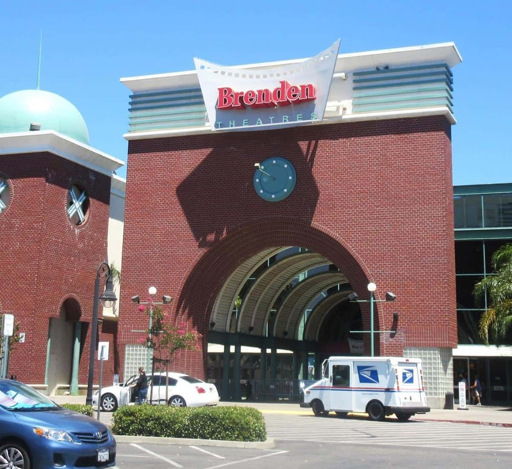 Brick theater entrance with "Brenden" sign and USPS mail truck, easy access parking, sunny day.