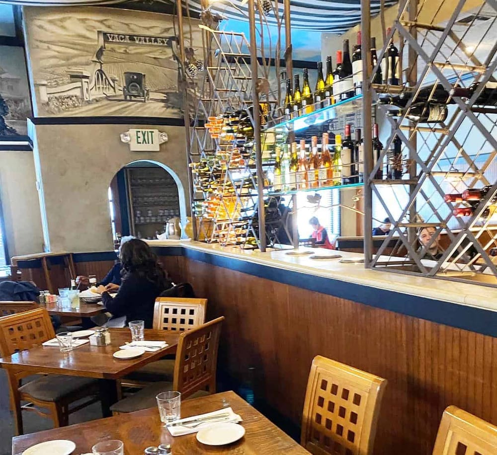 Rustic wine bar interior with wine bottles and decorative metal shelving at QuestForDirections restaurant.