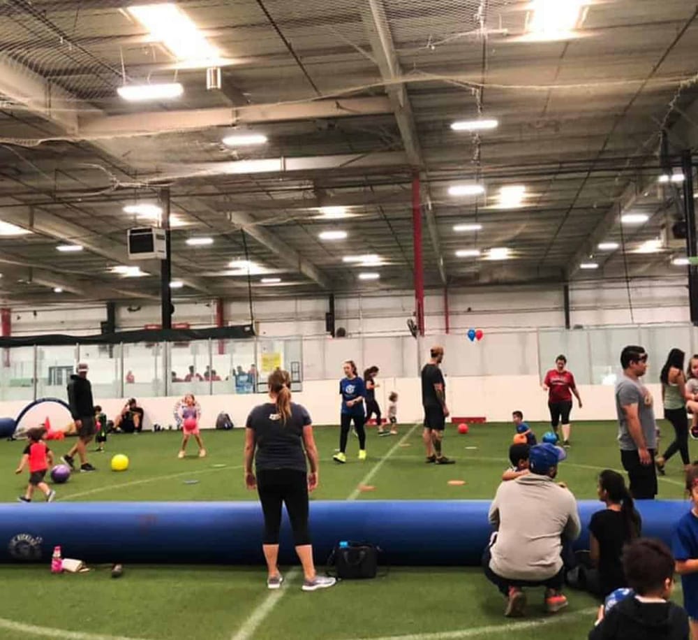 Indoor soccer training facility with kids and families playing and practicing soccer drills.