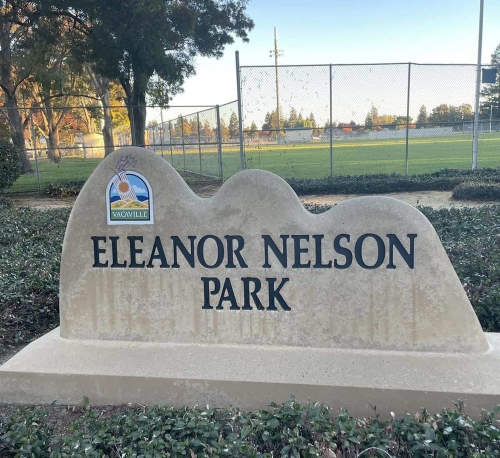Eleanor Nelson Park sign in Vacaville with sports field in the background.