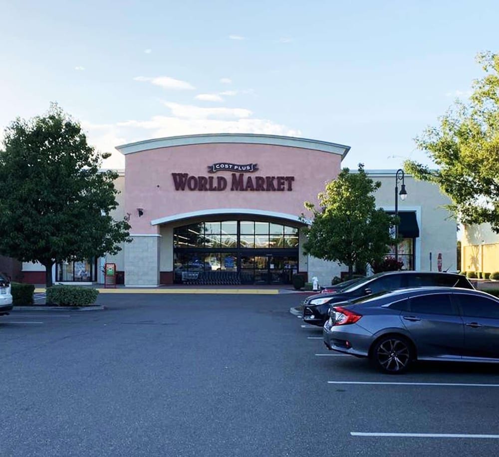 Colorful shopping mall entrance for world market, with parking lot and trees.
