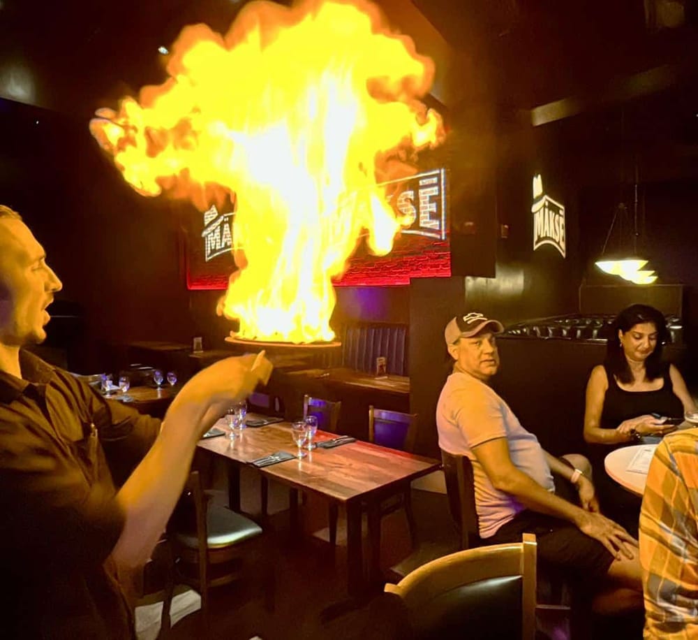 Flaming chef at a restaurant, creating a dramatic fire display for diners.