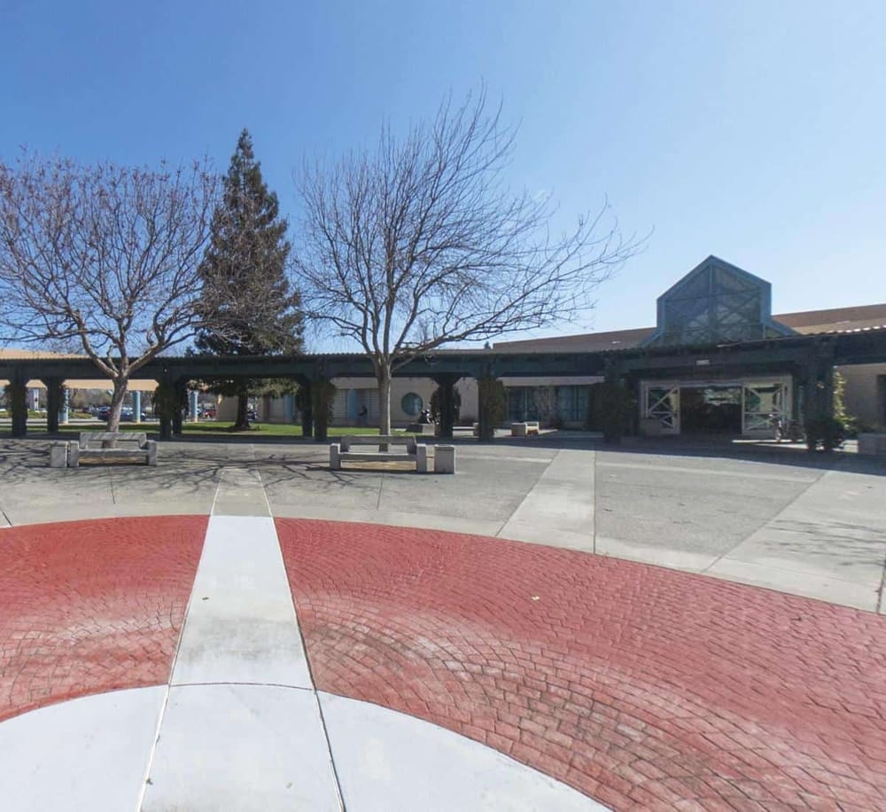Outdoor school campus with leafless trees, brick pathway, and modern building structure.