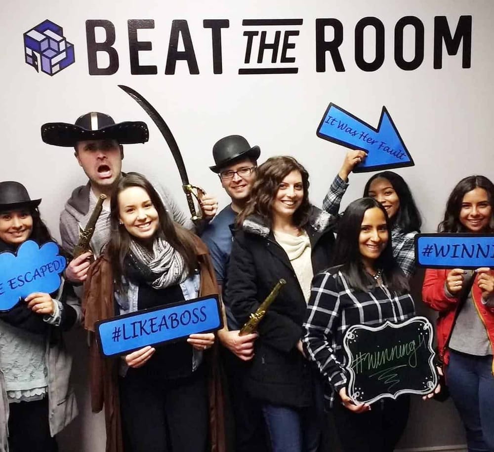 Escape room team celebrating victory with props and signs at QuestForDirections.