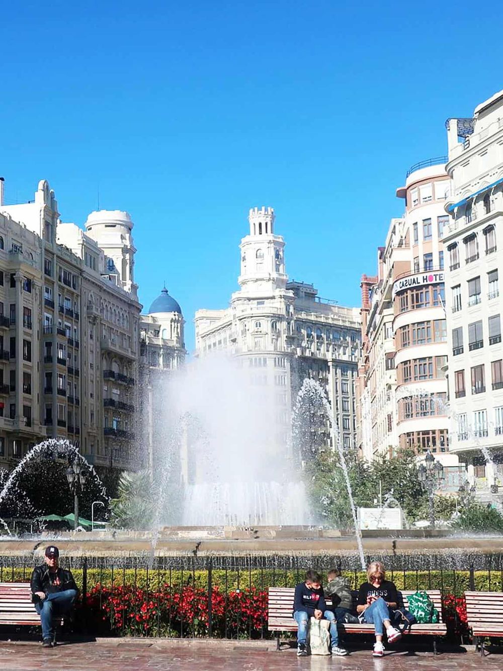 Colorful city square with historic buildings and a central fountain, ideal for sightseeing and urban exploration.