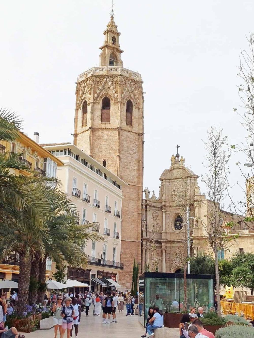 Historic bell tower and lively city square in Valencia, showcasing architecture and local culture.