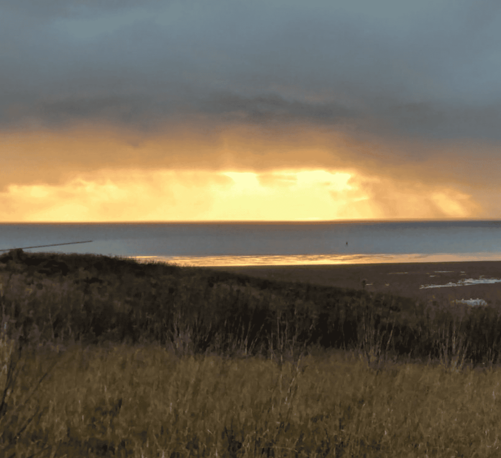 Serene coastal sunset view showcasing dramatic clouds and calm ocean waters for travel and nature enthusiasts.
