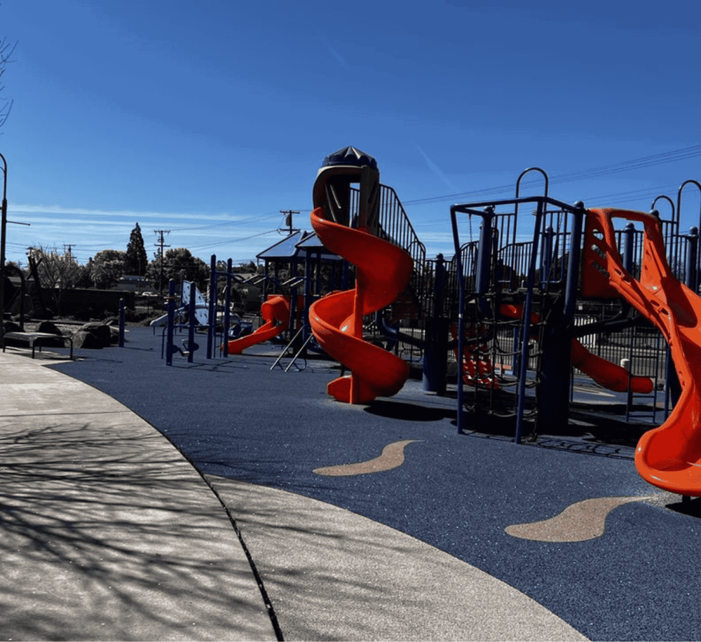 Bright playground with orange slides and climbing structures at QuestForDirections park.