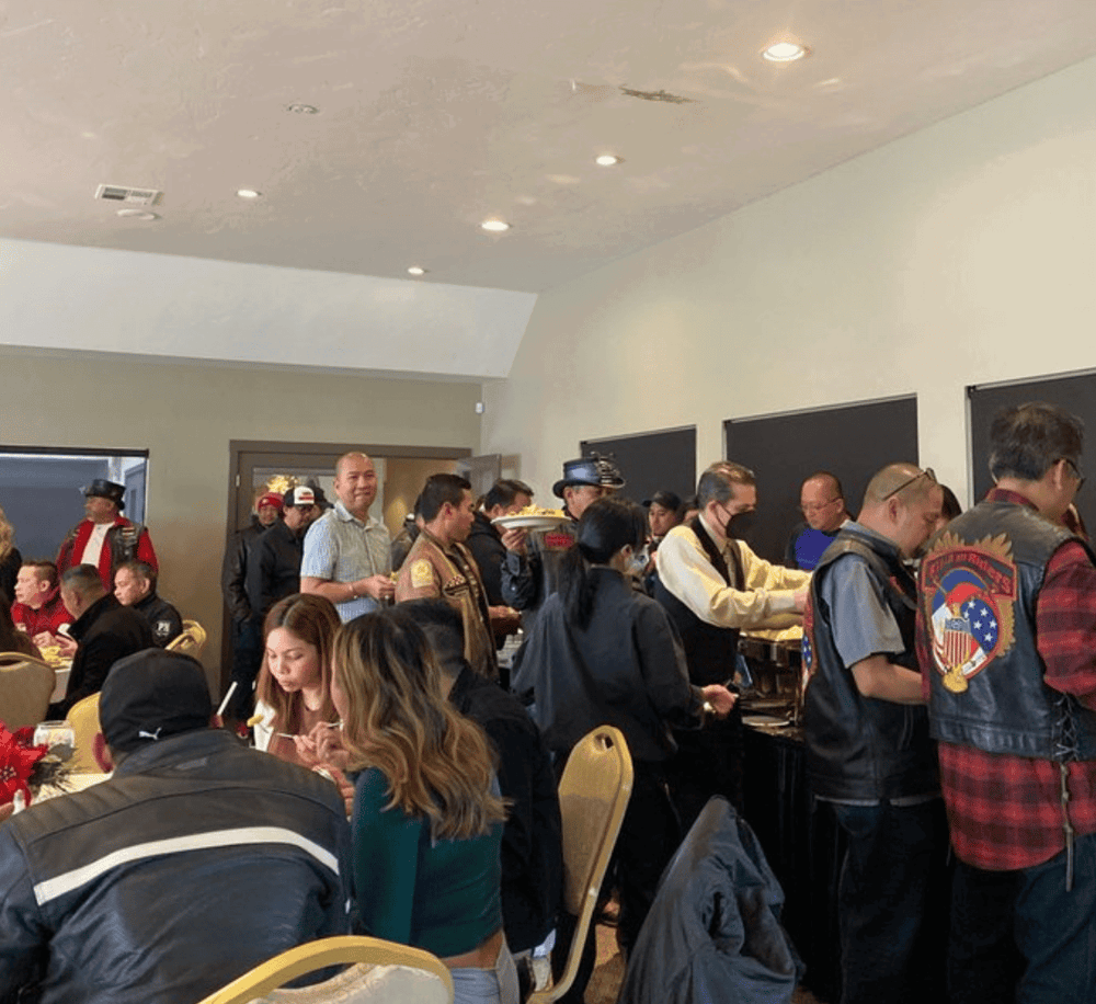 People enjoying a buffet at a community event or gathering, with diverse attendees and food service.