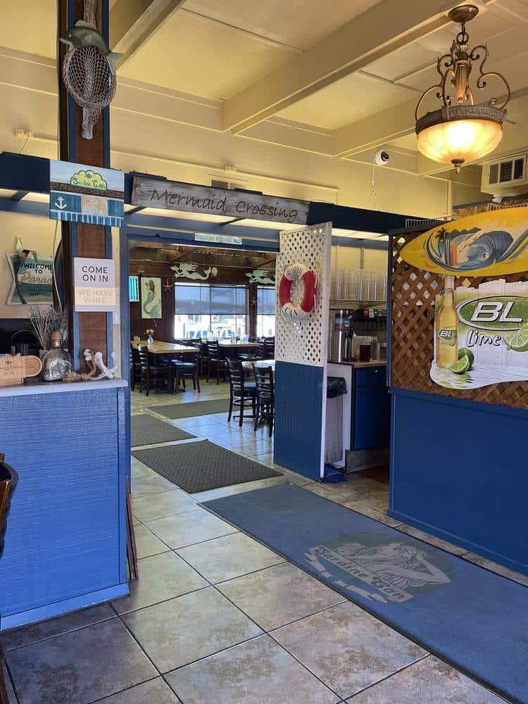Colorful ocean-themed restaurant entrance with "Mermaid Crossing" sign and beach decor, perfect for coastal dining experiences.