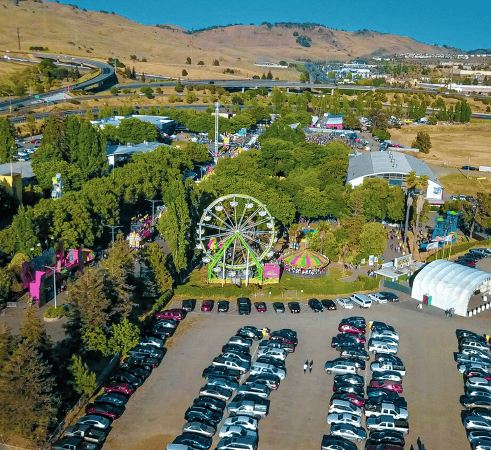 Bright amusement park with Ferris wheel, attractions, and parking lot, perfect for family fun and entertainment.