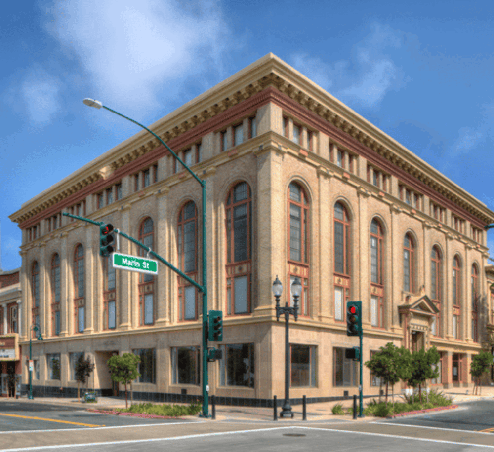 Historic downtown building on a corner with street signs for "Main St", sunny blue sky background.
