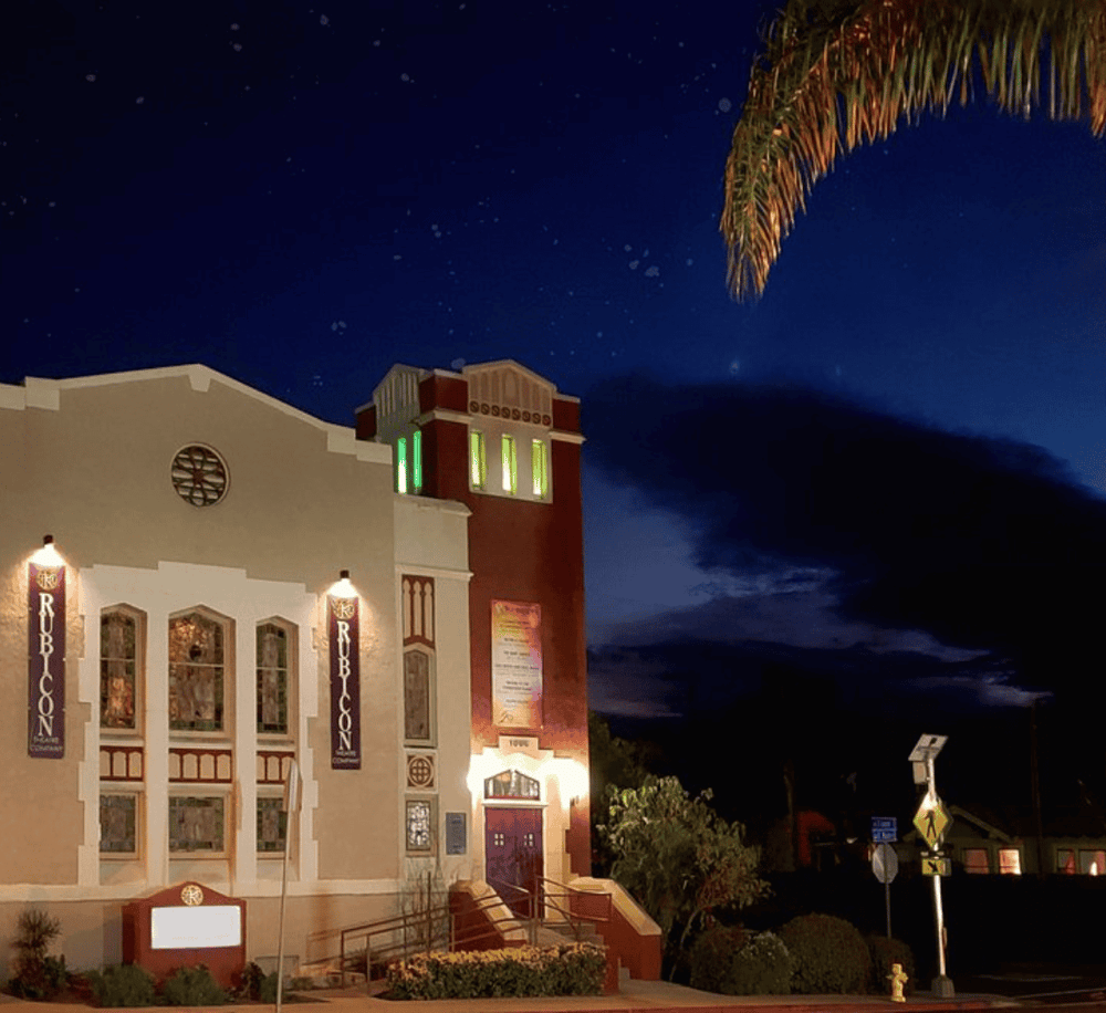 Charming town theater illuminated at night with starry sky in the background, showcasing vibrant local architecture.