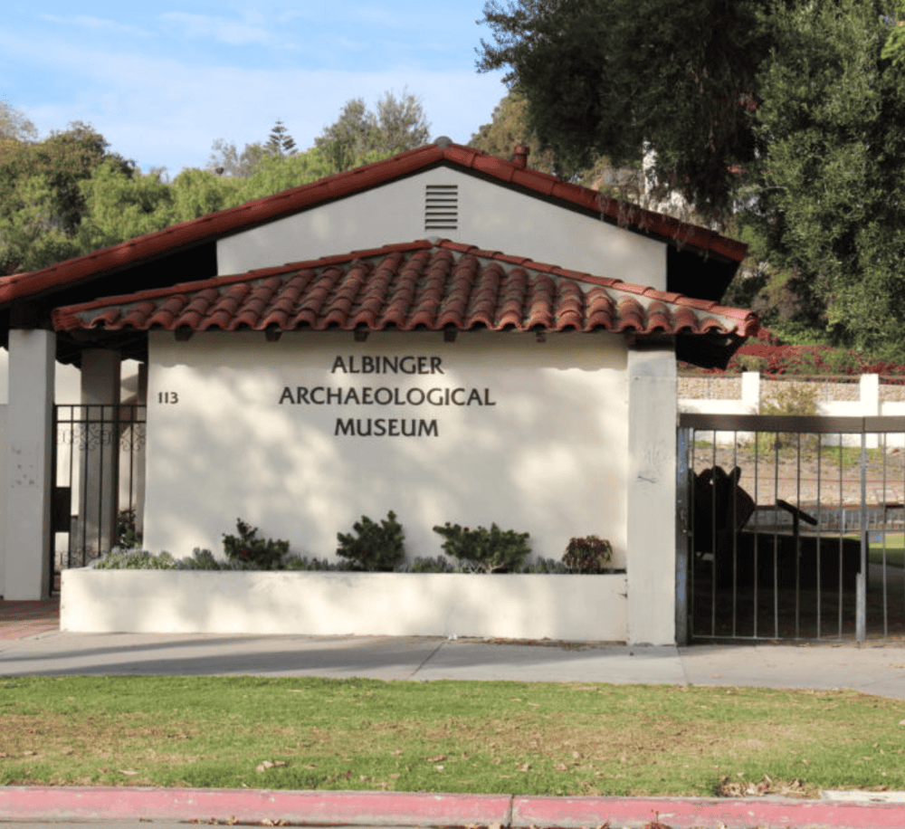 Archaeological museum in Albinger, historic building with Spanish tile roof, outdoor garden, and signage, in a lush setting.