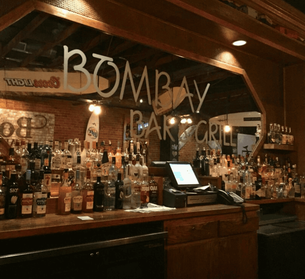 Bourbon bar with hanging mirror and liquor bottles at Bomaay Bar & Grill, warm indoor ambiance.