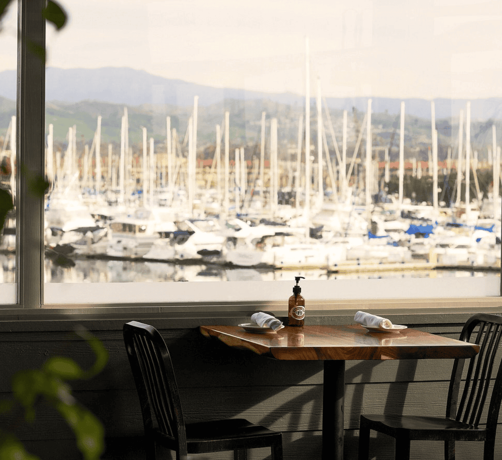 Serene marina view with yachts and mountains, perfect for relaxing dining experiences.