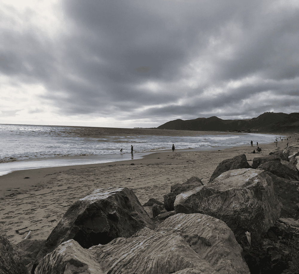 Beach with rocks and cloudy sky, scenic coastal landscape for travel and outdoor adventures.