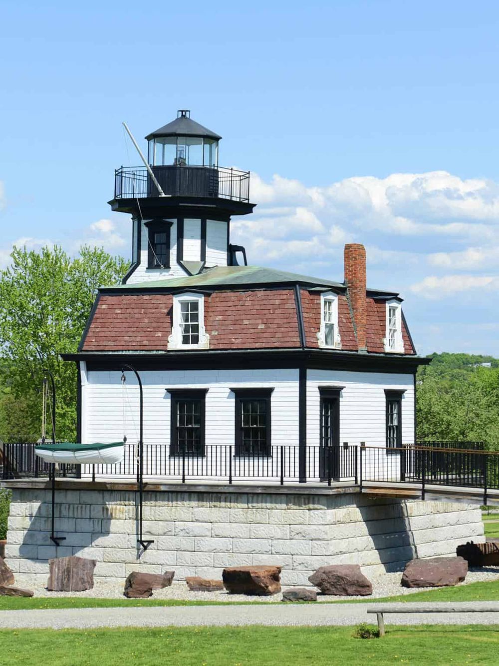 Historic lighthouse building with a white wooden exterior and black trim, situated in a scenic park setting.