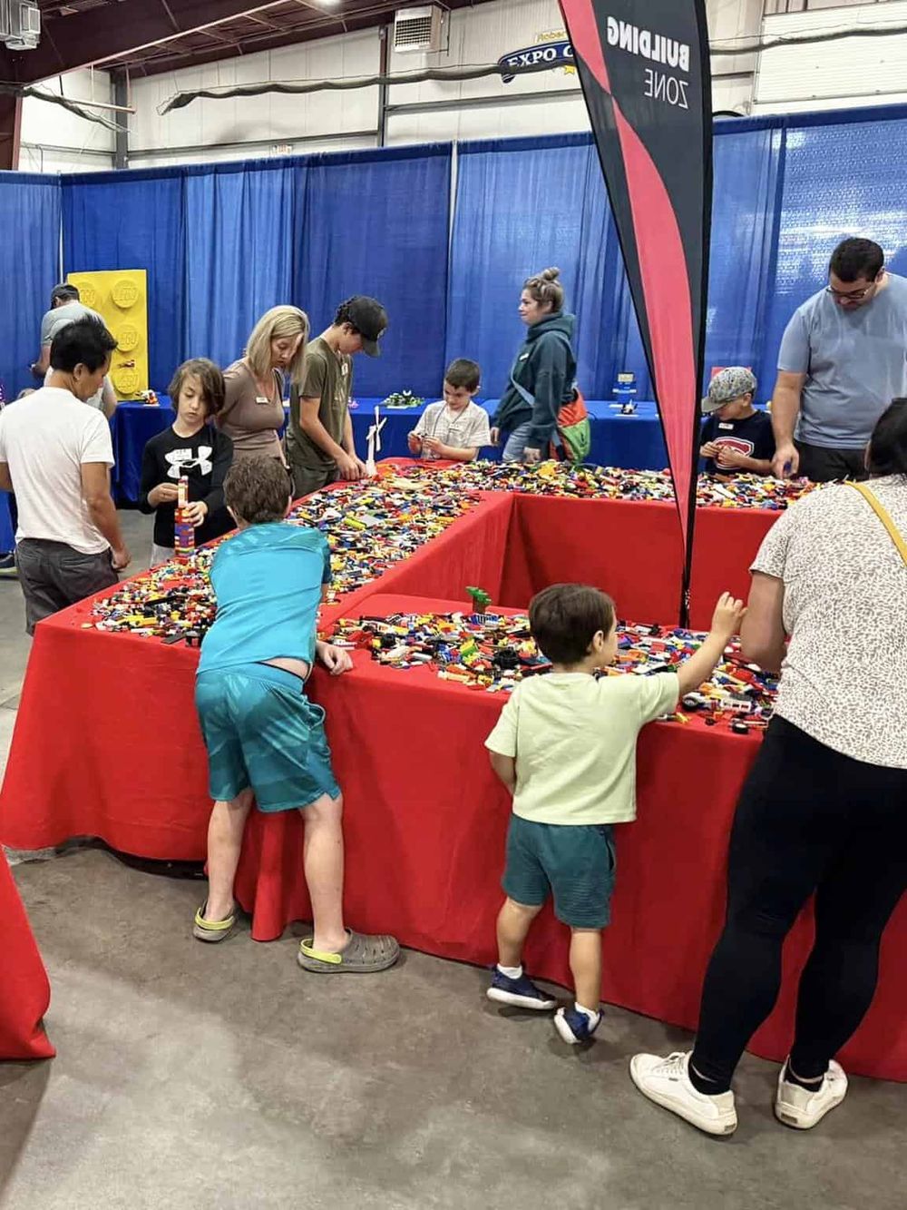 Colorful LEGO build activity at an indoor event with children and adults participating.