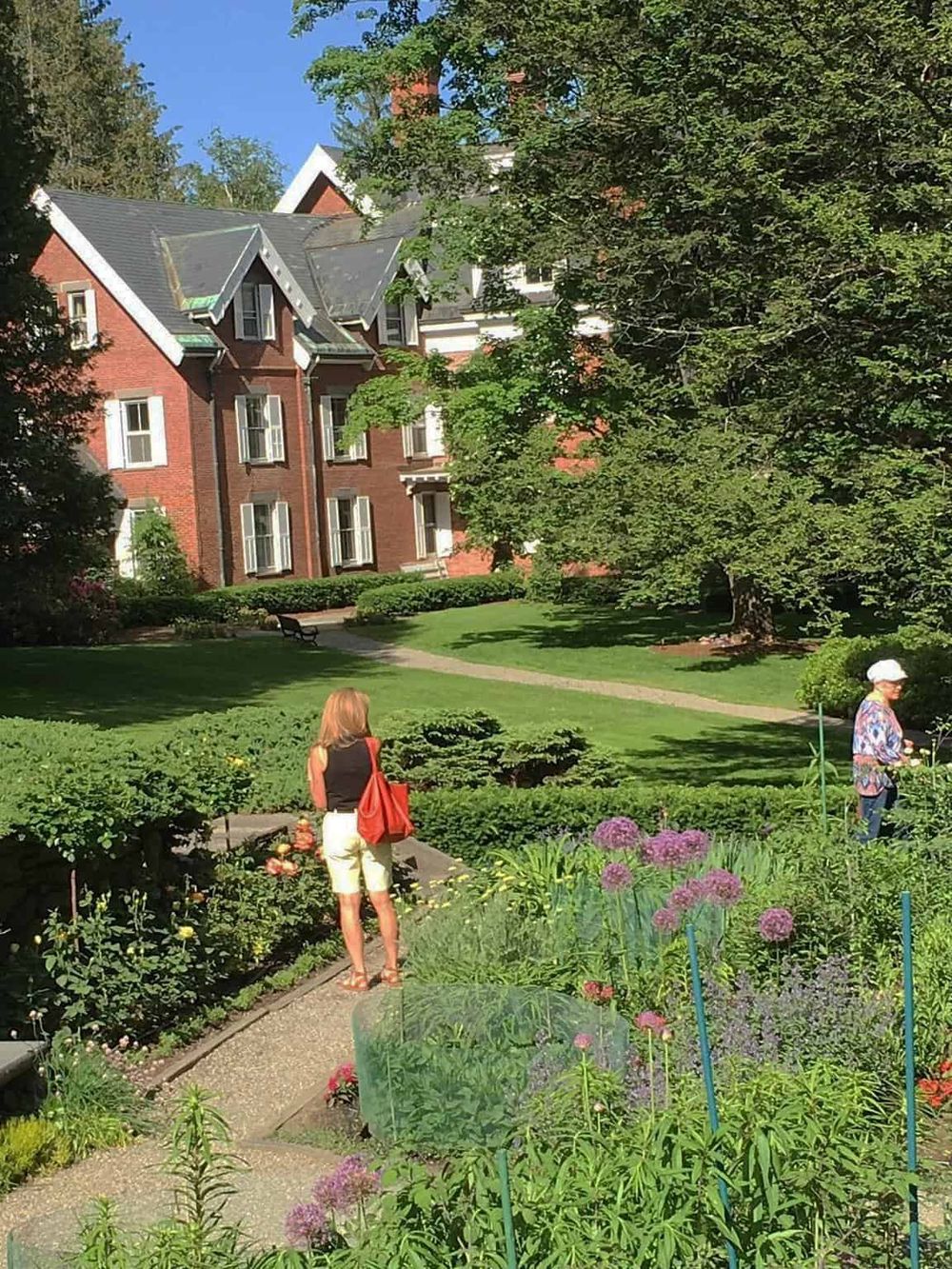 Lush garden with people, historic building, and vibrant flowers at QuestForDirections.