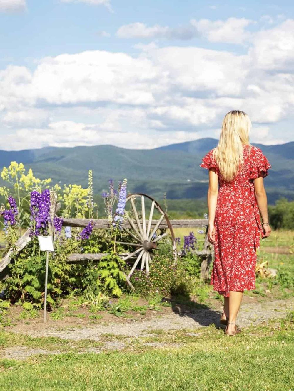 Serene woman walking in lush garden with mountain view in background, highlighting outdoor exploration and travel.