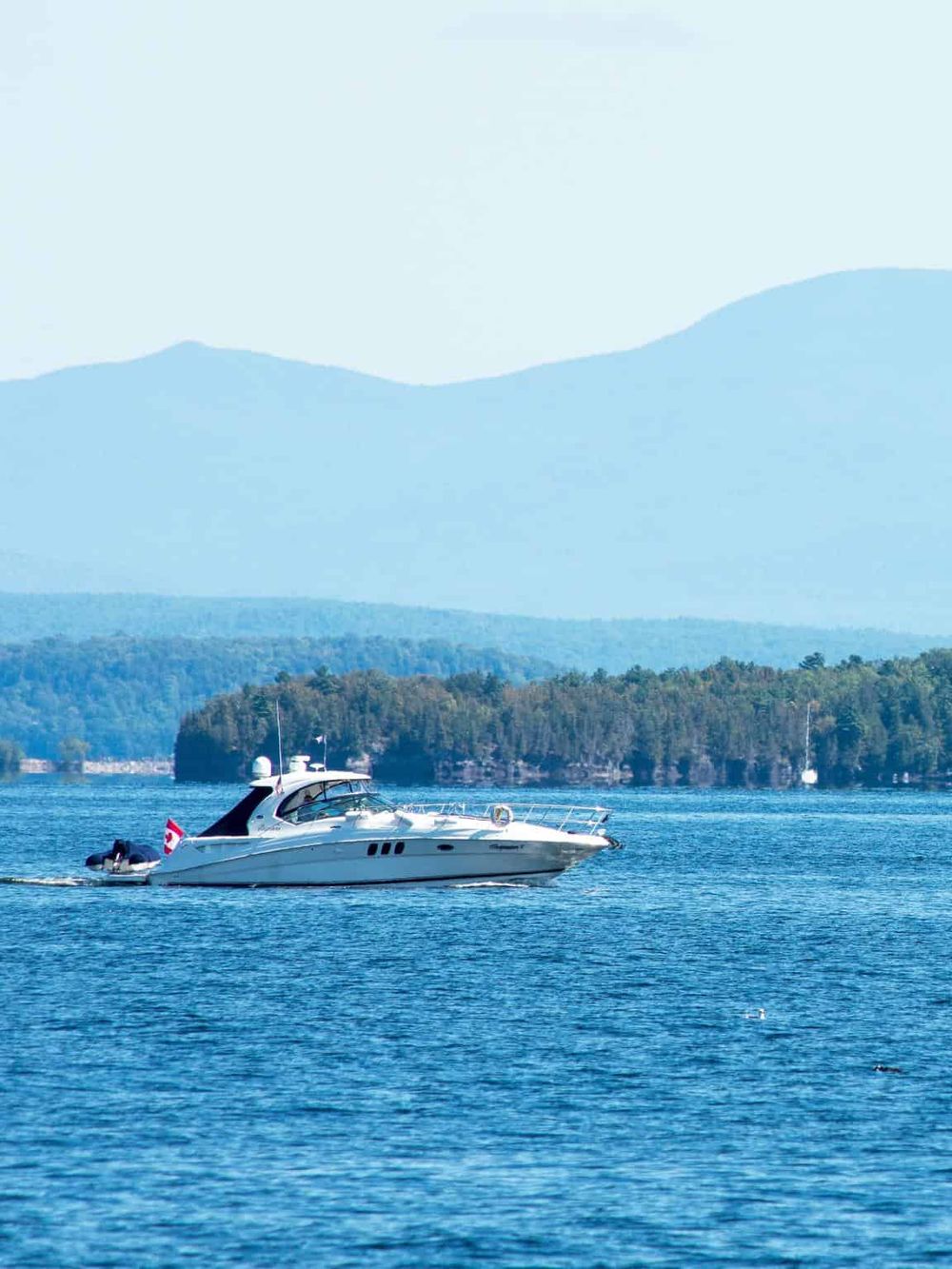 Luxurious yacht sailing on a scenic lake with mountains in the background, showcasing adventure and exploration.