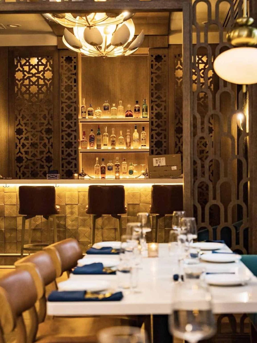 Luxurious bar with illuminated bottles and elegant wooden decor, perfect for a refined dining experience.