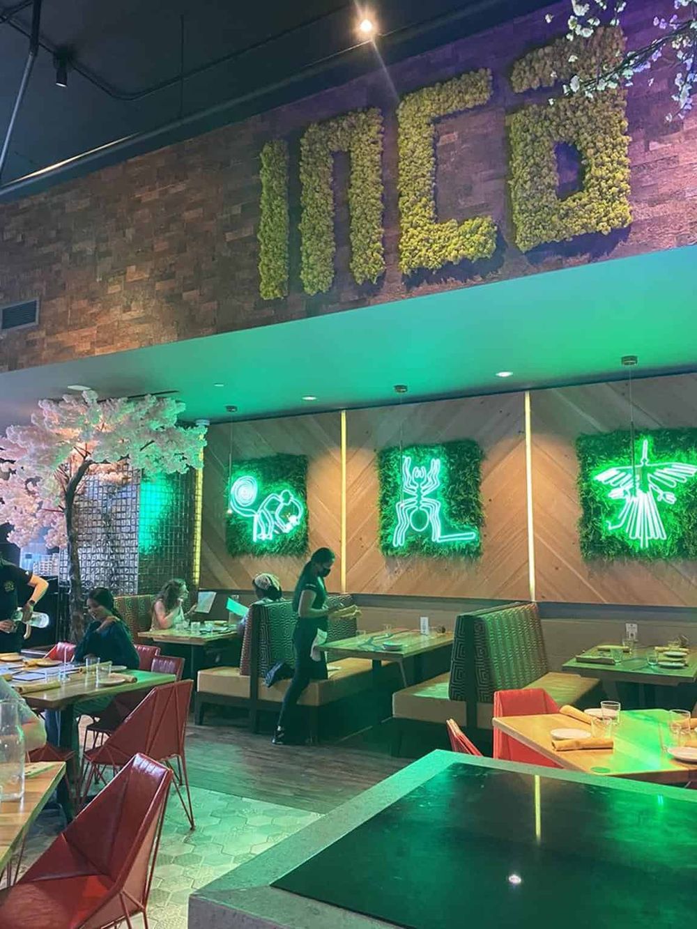 Decorative restaurant interior with neon art and lush greenery, creating a vibrant dining atmosphere.