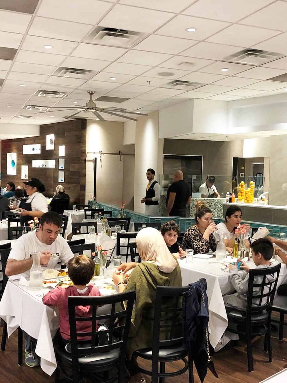 Busy restaurant interior with diverse diners and staff serving | QuestForDirections dining experience SEO.