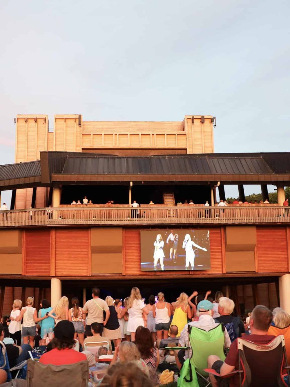 Outdoor concert at QuestForDirections, large crowd enjoying live music on a warm evening.