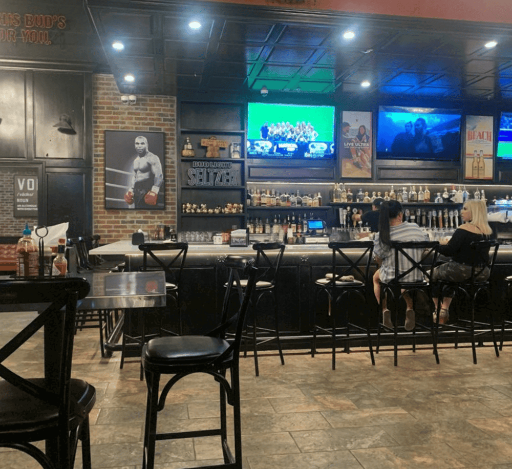 Cozy sports bar with multiple TV screens, hardwood floors, and diverse drink options for sports fans.