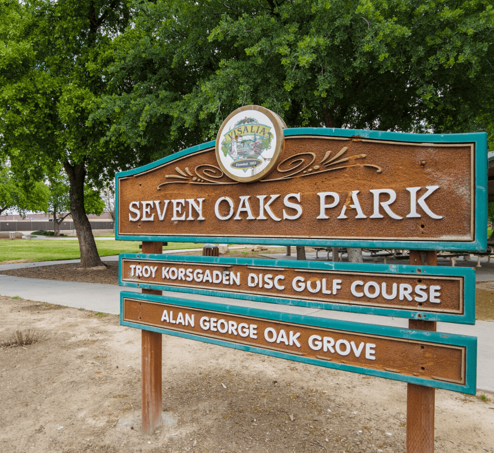 Visalia Seven Oaks Park sign promoting local golf courses and community amenities.