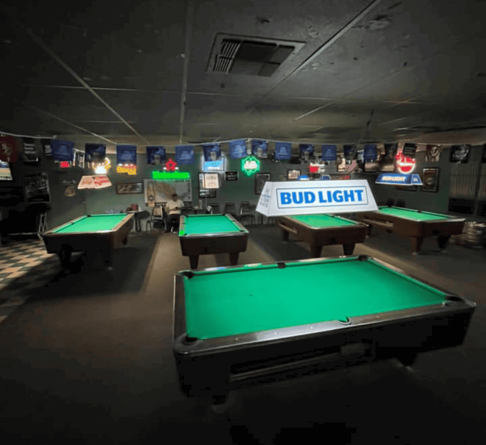 Pool hall with multiple pool tables and neon signs, ideal for billiards enthusiasts.