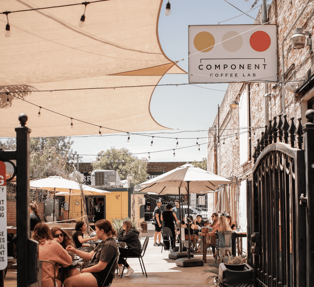 Enjoy outdoor dining at Component Coffee Lab in a vibrant, stylish courtyard setting with string lights and modern decor.