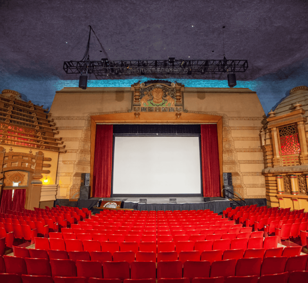 Empty theater with large screen and ornate architecture, perfect for film screenings and live performances.