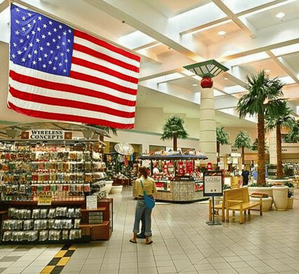 American flag shopping mall decor, indoor retail space, souvenir shop, holiday decoration, tropical palm trees.