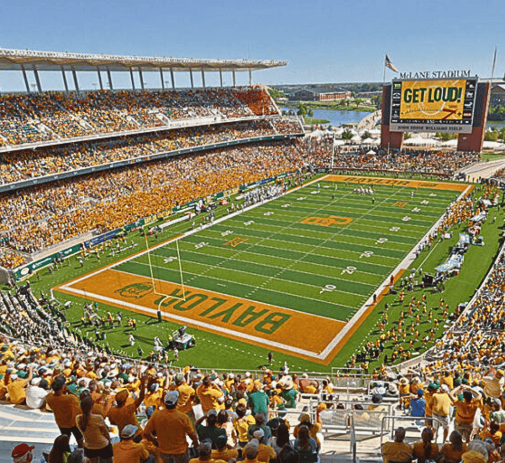 Vibrant football stadium packed with fans, field ready for game, bright sunny day in a scenic city setting.