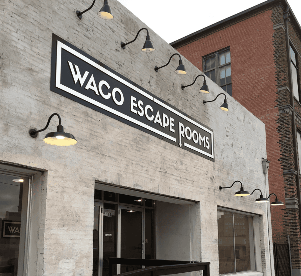 Waco Escape Rooms sign on a brick and concrete building, perfect for team-building activities.