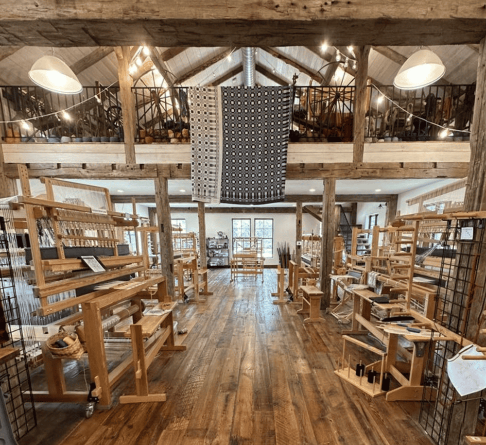 Handmade weaving studio with rustic wooden furniture and looms for fiber arts and textile crafts.