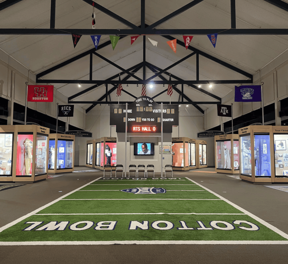 1. Interior sports memorabilia museum at Quest for Directions with college team banners and interactive displays.