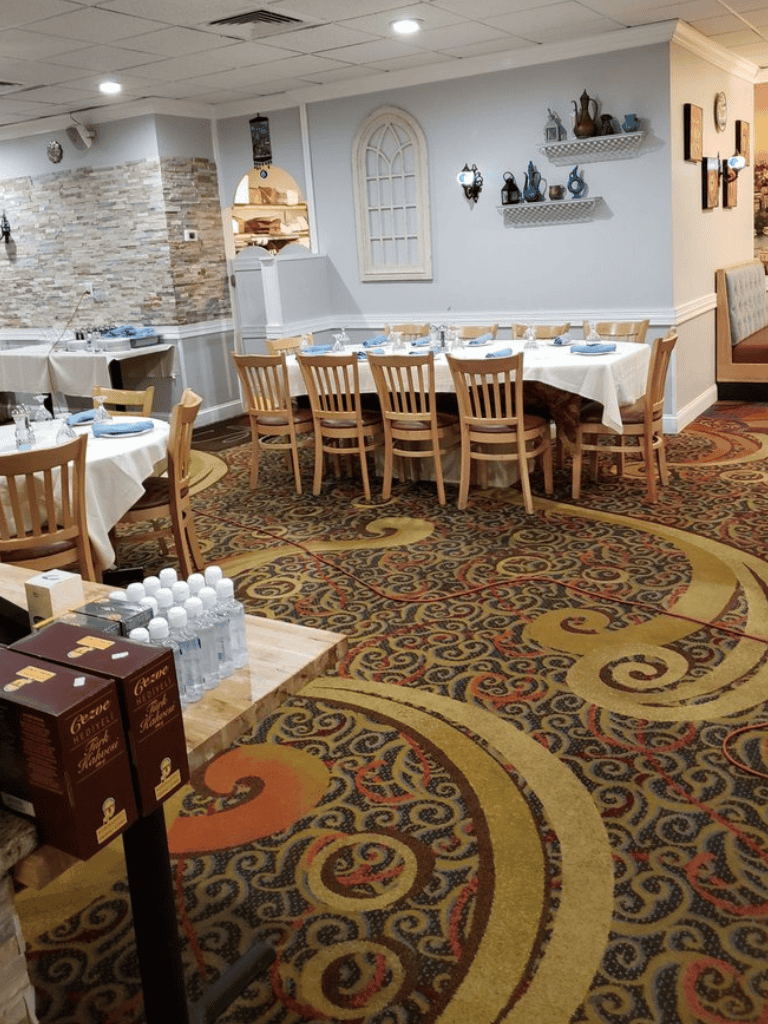 Cozy restaurant dining area with round tables, elegant decor, and patterned carpet.