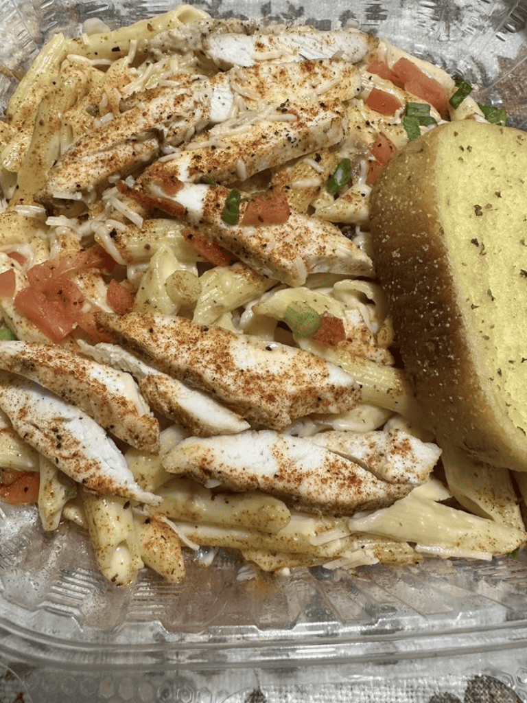 Grilled chicken pasta salad with tomatoes and green onions, served with garlic bread. Fresh, flavorful, and perfect for lunch or dinner.