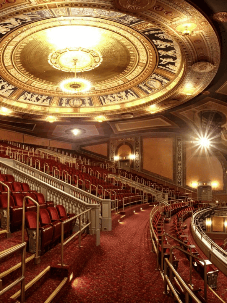 Luxurious theater auditorium with ornate ceiling and red seating for live performances and events.