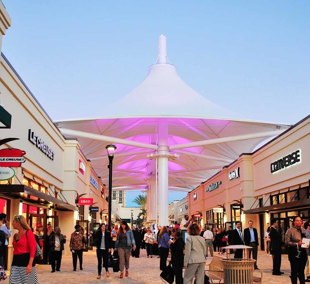 Bright outdoor shopping mall with popular retail stores and a large distinctive canopy structure.