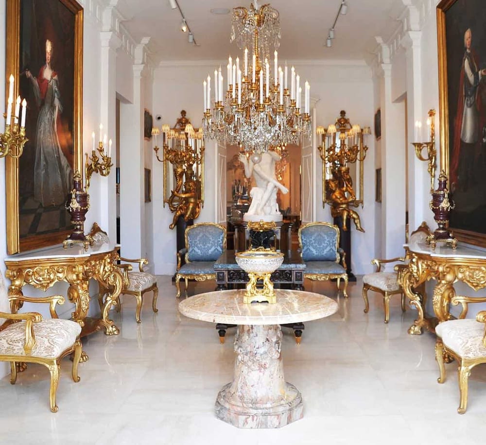 Luxurious interior with ornate gold accents, chandelier, and classical sculptures, showcasing elegant design.