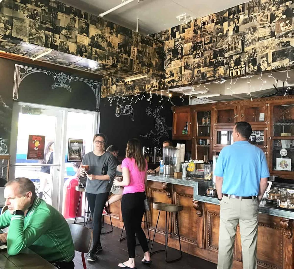 Cozy coffee shop interior with baristas and customers enjoying drinks and conversation.