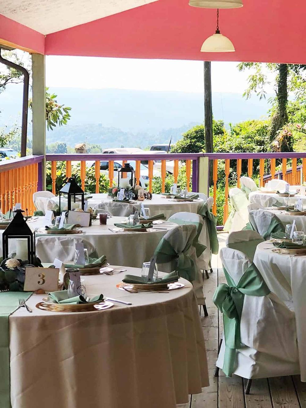 Elegant outdoor wedding reception with scenic mountain view, decorated tables, and floral accents.