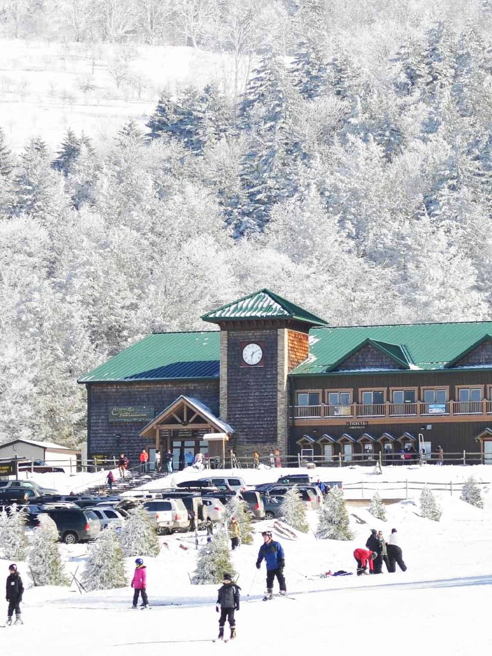 Snowy mountain lodge with skiers and visitors, scenic winter destination for outdoor adventures.