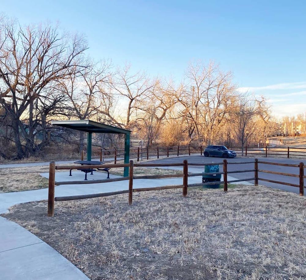 1. Snow-covered park with picnic table, trees, and a car in the background, in winter scenery.