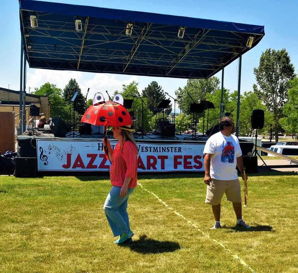 Colorful jazz festival stage with performers and audience in lush outdoor setting, celebrating jazz music.